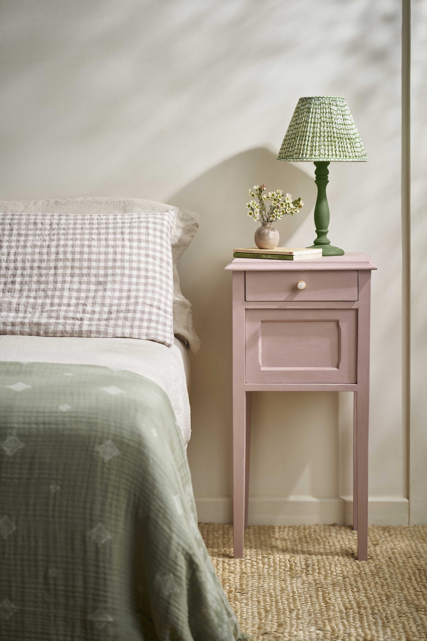 Jaipur Pink Annie Sloan Chalk Paint painted nightstand with a green lamp next to a bed with checkered pillow and green blanket