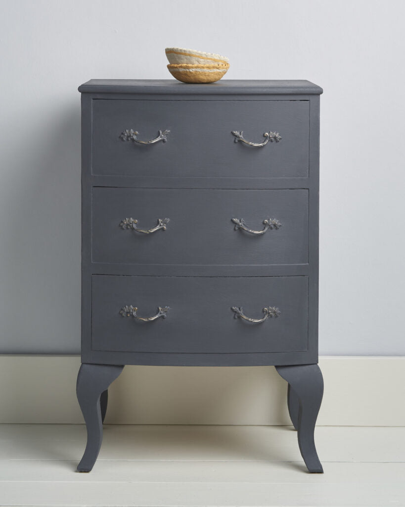 Whistler Grey by Annie Sloan Chalk Paint painted dresser with four drawers and decorative handles on a light gray background